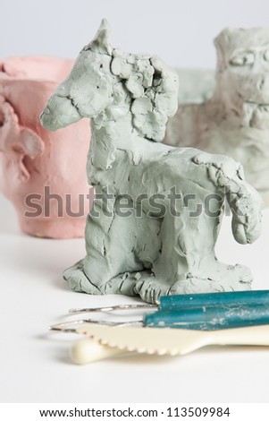 Modelling a horse from clay or plasticine in a creative craft class with sculpting tools in the foreground