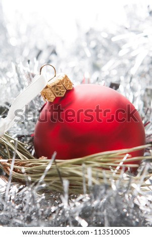 Shiny deep red Christmas ball with glittering silver tinsel and copyspace for your festive greetings or message
