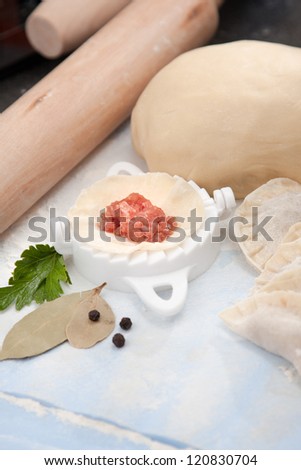 Preparing pelmeni using a pastry cutter to shape and flute the unleavened dough shell