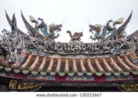 Two brightly colored dragons surround a small creature on the top of the traditional entrance pagoda to the Mengjia Longshan temple in Taipei, Taiwan.