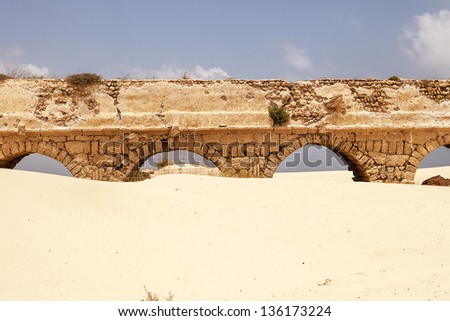 Remnants of the old Roman stone aqueduct that supplied water to the ancient city of Caesaria, now in Israel. The sands of the beach have almost reached the tops of the arches.