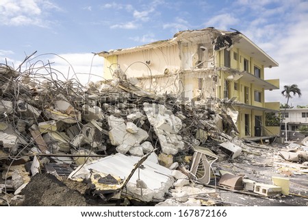The last standing section of a hotel in the final stages of demolition with a large pile of jumbled concrete, steel rebar, and other debris in front waiting to be hauled away.