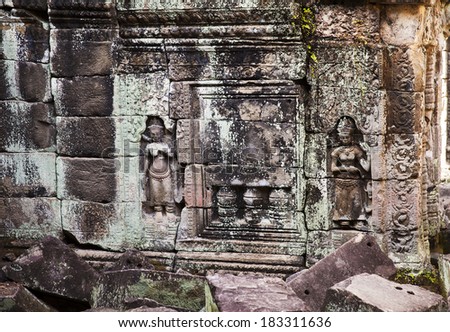 Two small carvings of women flank a fake stone window in a well at the ancient Preah Khan temple near Angkor Wat.