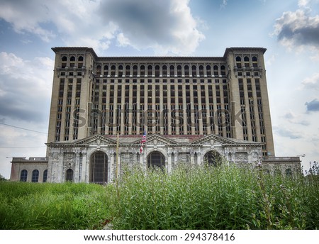 DETROIT, USA - JUNE 9, 2015: A view of the front facade of the Michigan Central Railway Station as seen over weeds growing in front of the building. The historic landmark is in disrepair.