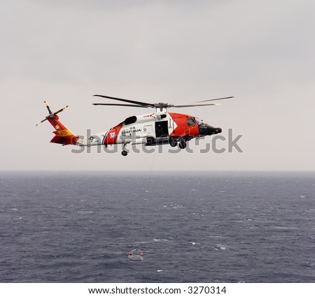 A United States Coast Guard helicopter lowering a rescue basket during an air-to-sea rescue mission. The Blackhawk copter was hovering over the bow of a cruise ship while evacuating an ill passenger.