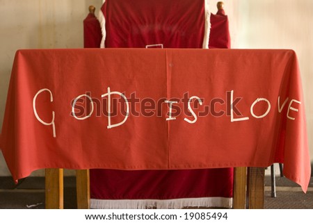 A handmade cloth saying God Is Love. This covers the altar of a make-shift church in the township of Kayamandi, South Africa.