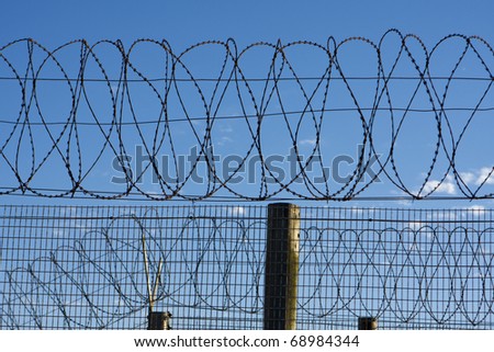 Coils of barbed wire atop a fence provide security at a penitentiary in South Africa. The barb wire symbolizes protection and security -- but also the freedom beyond the perimeter of the prison walls.