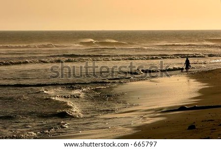 Person walking into the light along the shoreline of the Pacific Coast ocean
