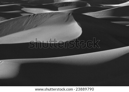 Sand dunes at Death Valley National Park in black and white with the sun beating on them in California, USA
