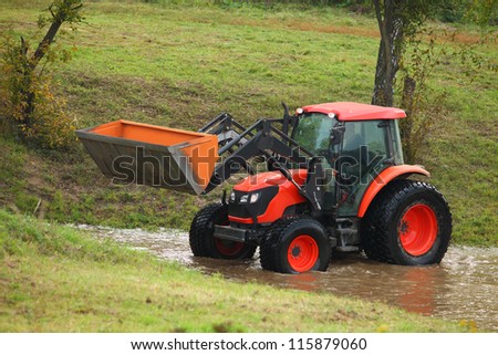 Tractor repair of rural roads, which flooded and blurred the rain