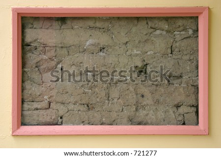 A framed area of an old wall shows the adobe bricks hidden below the surface.