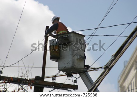 An electrician, high on a lift, works the wires.