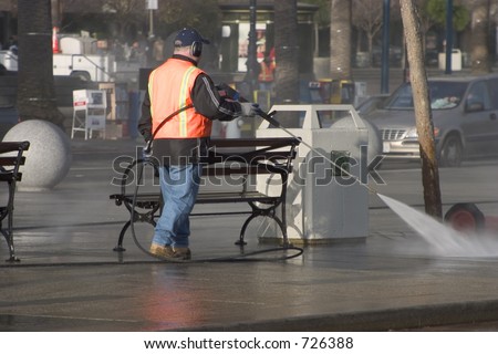 A city worker steam-cleans the sidewalk.