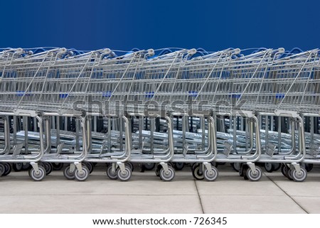 A line of shopping carts against a blue wall.