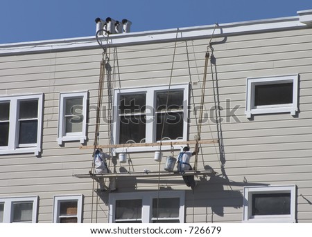 Two men lower themselves the side of an apartment building.