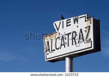 A bird sits atop a broken old sea-side neon sign that reads â€œView Alcatrazâ€�.