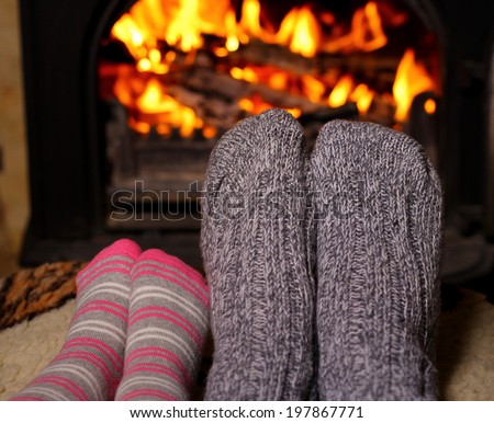 Mom and daughter warm their socked feet by the fire
