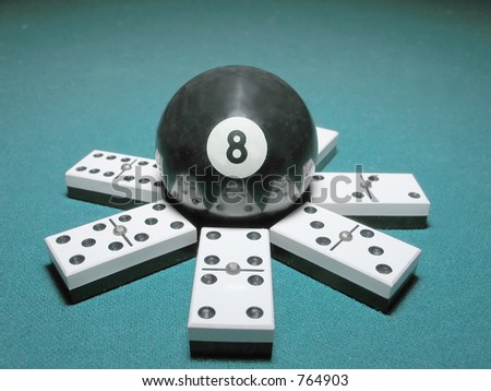 Eight ball from billiard game on top of a seven domino double structure.