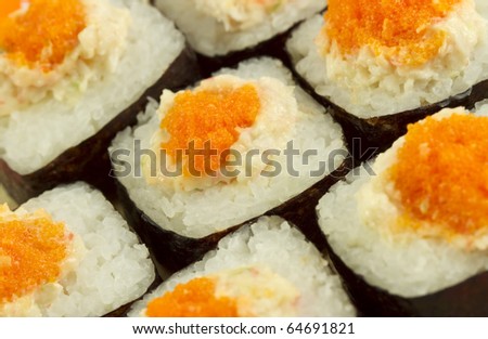 Masago eggs seen close up on a rice roll with the nori sea weed on the outside.