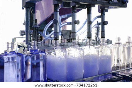cosmetic industry, detail of filling glass bottle with blue eau de toilette