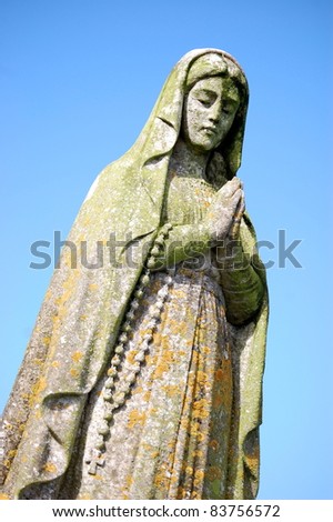 Worn Statue of Mary A statue of Mary taken in an Irish Church Graveyard.  Hands held together with Rosary Beads hanging down.