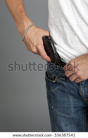 Gun inserted by the waist of jeans at the young man