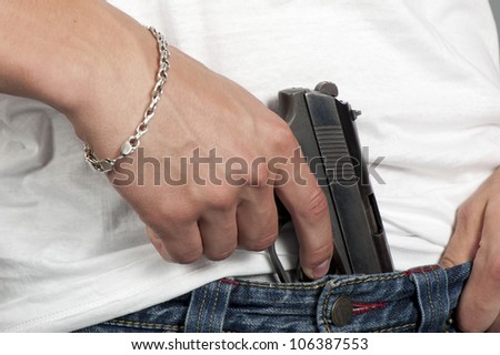 Gun inserted by the waist of jeans at the young man