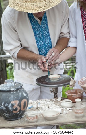 Master Potter teaches young woman working on a Potter\'s wheel