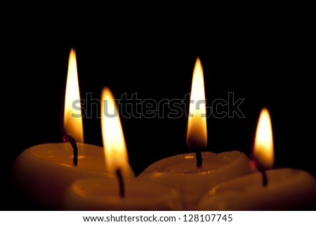 Four outstanding paraffin candles on a black background close-up
