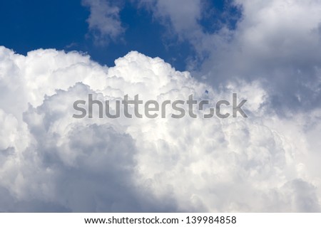Cumulus clouds lit up by the Sun on the summer blue sky