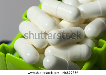 Capsules with medication in a container of baby toy tractor closeup