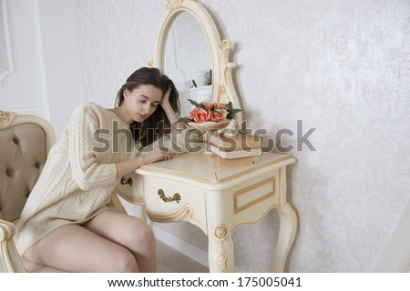 The young woman fell asleep at the table in front of the mirror