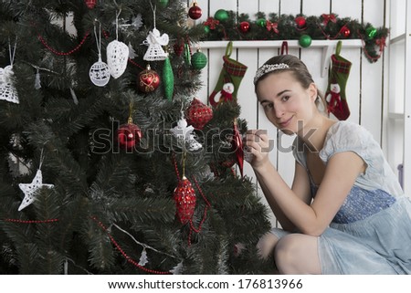 Girl next to the beautifully decorated Christmas tree in white dress