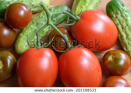 Ripe red tomatoes and cucumbers on the plate is brightly lit close up