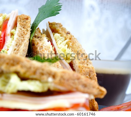 close up fresh and delicious classic club sandwich over a black glass dish with coffee and vegetable