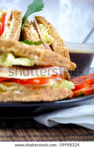 fresh and delicious classic club sandwich over a black glass dish with coffee and vegetable