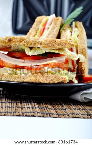 fresh and delicious classic club sandwich over a black glass dish with coffee and toasters