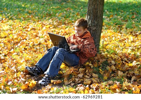 Child make fun with notebook under tree in autumn forest