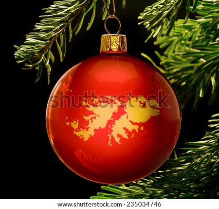 A red bauble with the golden shape of  Falkland Islands hanging on a christmas tree isolated on black.(series)