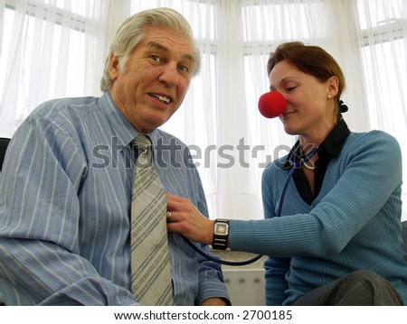 Doctor with red nose listening to his heart beat