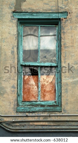 A broken window with peeling paint around the frame, and pipes running along the wall underneath.