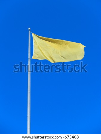 A yellow flag waves against a bright blue cloudless sky.