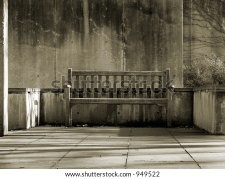 An empty wooden bench in a weathered concrete park.