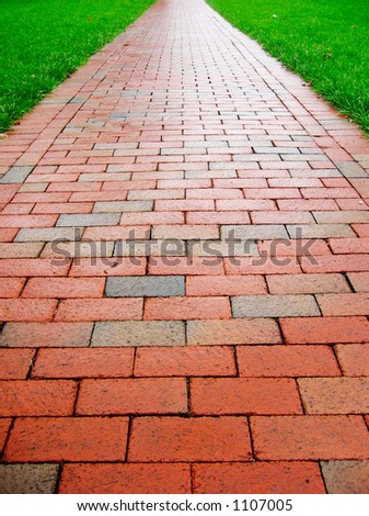 Straight brick path cuts through bright green grass.