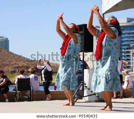 TEMPE, AZ - MARCH 31: Two unidentified women, wear print dress and lei, while they dance to HawIiaan music at the Dragon Boat Festival at Tempe Town Lake, March 31, 2012.