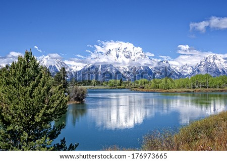 The snow-capped Grand Teton mountains in early summer rise majestically above the scenic Snake River in Grand Teton National Park.