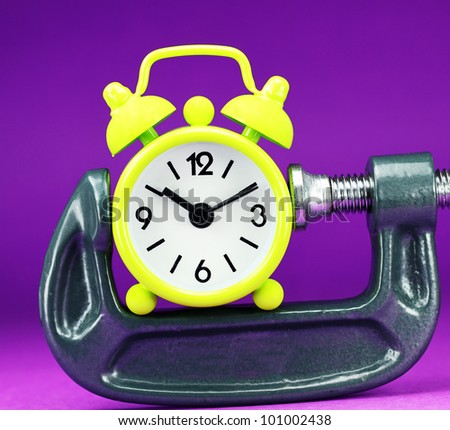 A lime green alarm clock placed in a Grey clamp against a pastel purple background, asking the question do you manage your time effectively.