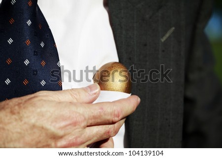A well dressed businessman pulling a golden nest egg from his shirt pocket, indicating this nest egg comes from the heart.