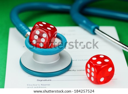 A Doctors desk with a dice placed on top of a blue stethoscope, with another dice placed on a doctors sick certificate pad, asking the question, do you gamble with your health