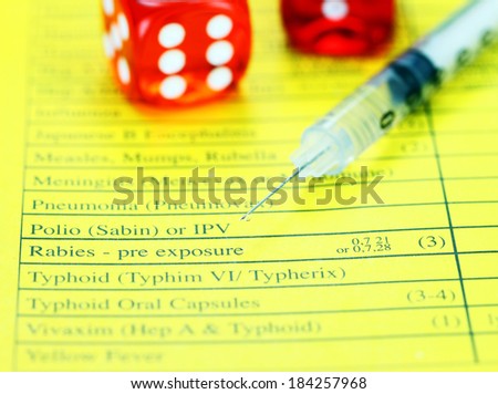 Two red translucent dice placed on a vaccination passport with a loaded syringe next to it, asking the question will you gamble by not having the proper vaccinations!